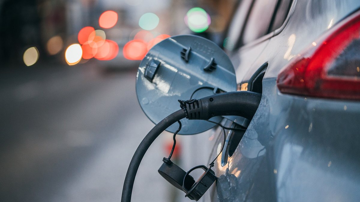 Close-up of an electric car charging. Traffic lights in a blurry background